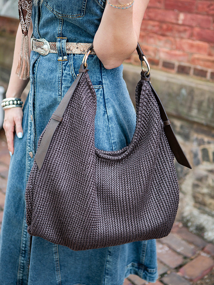 A woman carrying a large, dark-brown mesh tote bag.