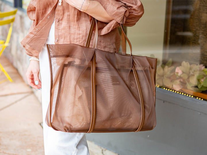 Person holding a brown tote bag outdoors
