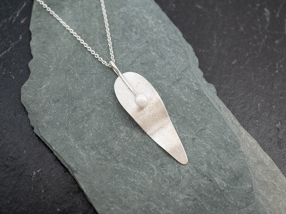 A necklace featuring a scoured silver leaf with a cultured pearl