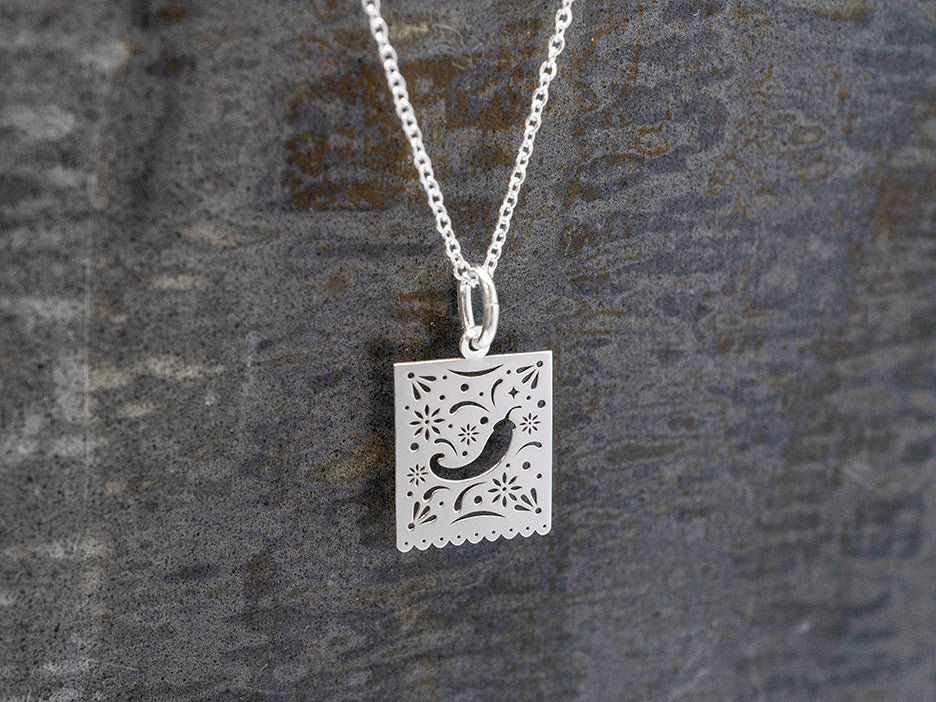 Silver necklace with a decorative pendant on a textured gray background