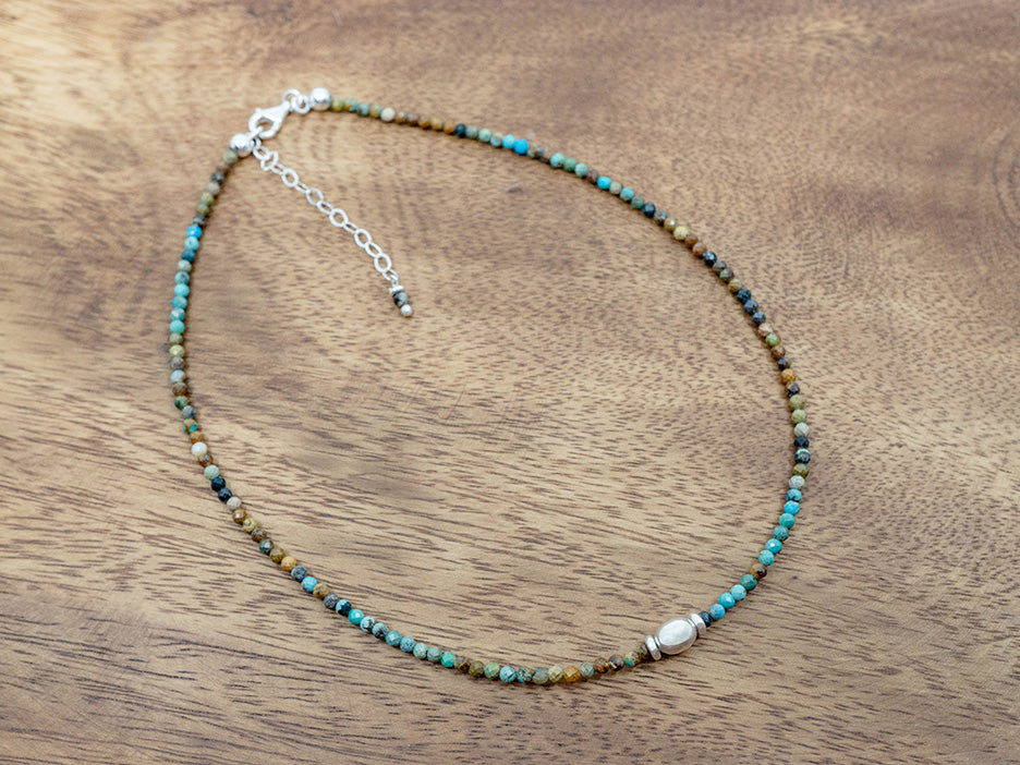 Beaded turquoise necklace on a wooden surface.