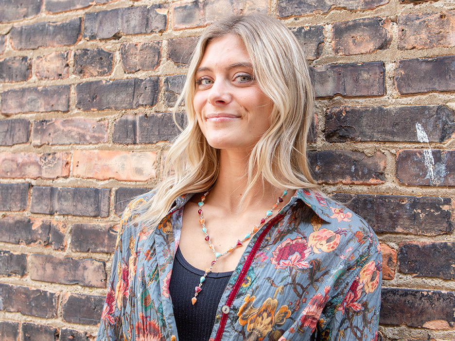 A model wearing a sterling silver lariat necklace made with teardrop and trillion cut multi-colored stones.