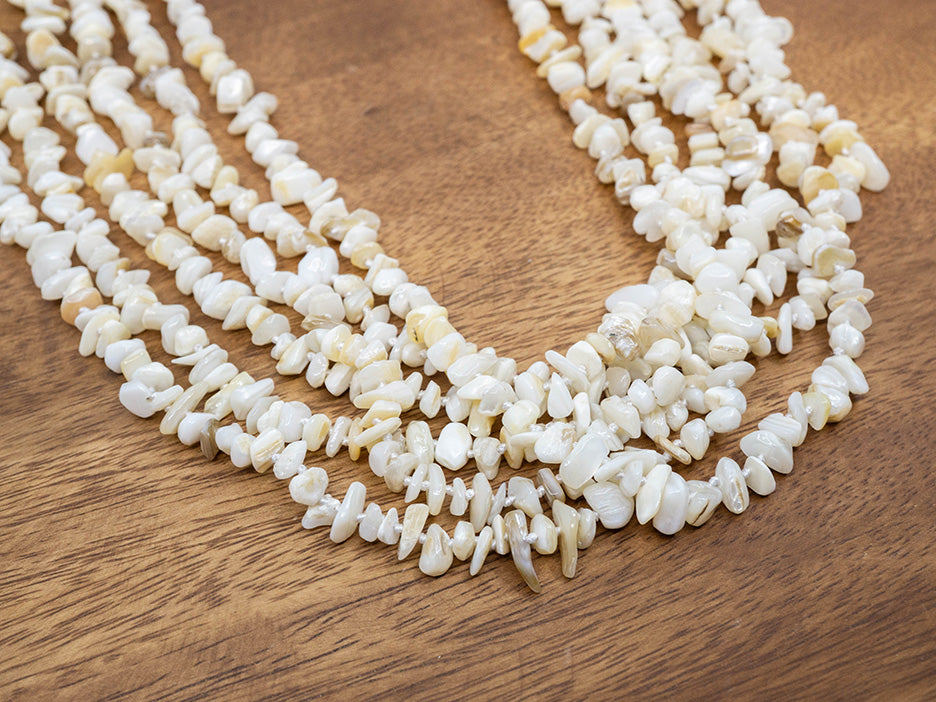 multi-strand white beaded necklace on a wooden surface