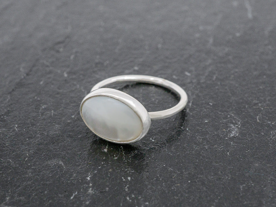 A simple silver band ring with an oval mother of pearl center