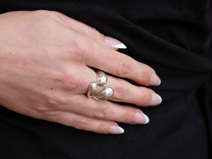 Hand wearing a silver ring with black background