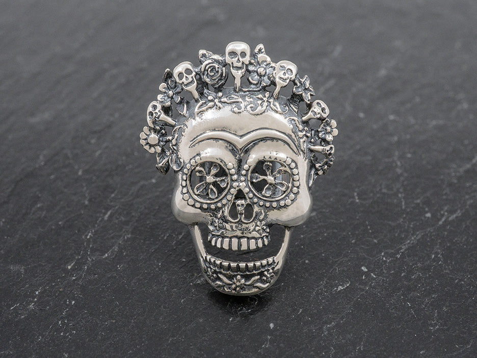 A silver ring with a large catrina face.