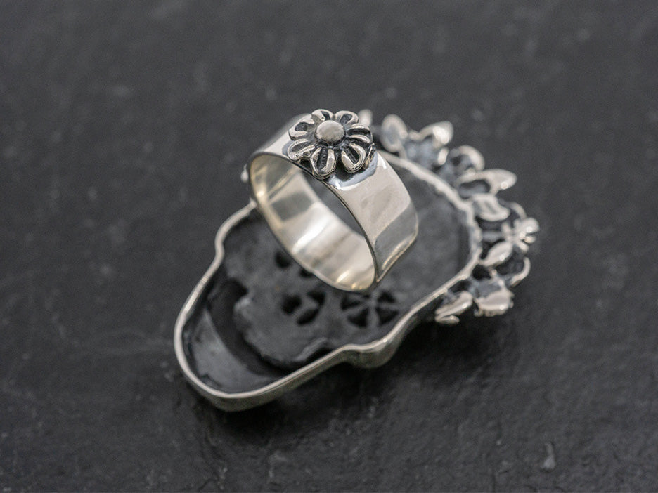 A silver ring with a large catrina face.