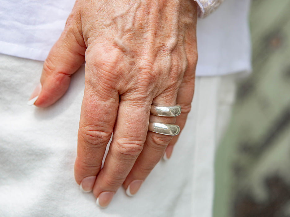 A hand wearing two silver rings on the ring finger.