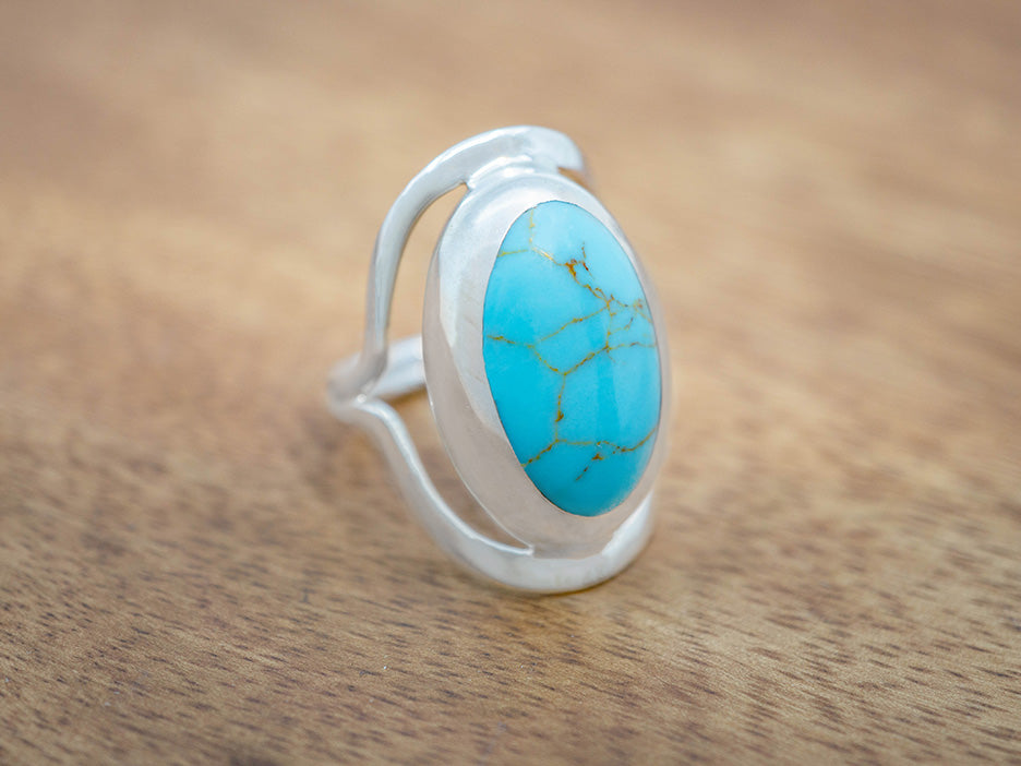 A large, oval sterling silver statement ring with a turquoise stone in the center.