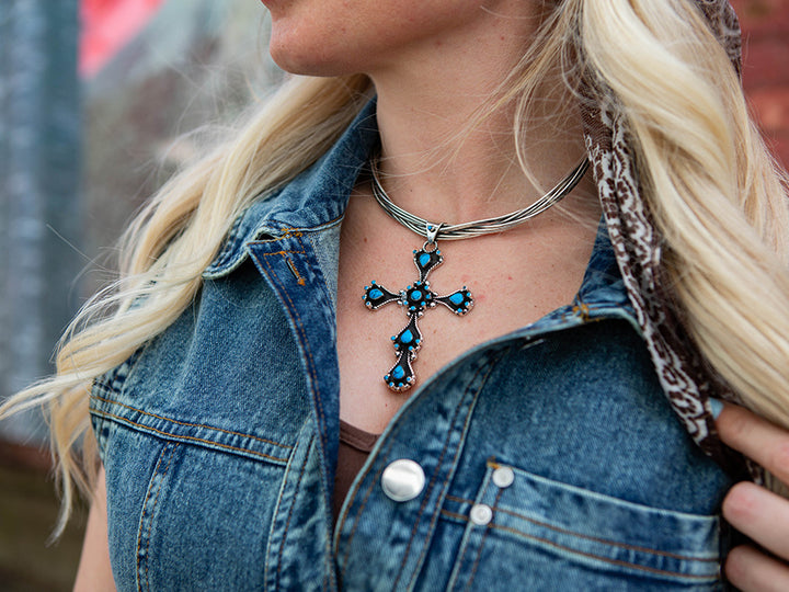 woman wearing a large cross pendant on a silver choker