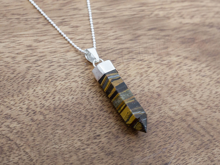 Necklace with a tiger's eye pendant on a wooden surface