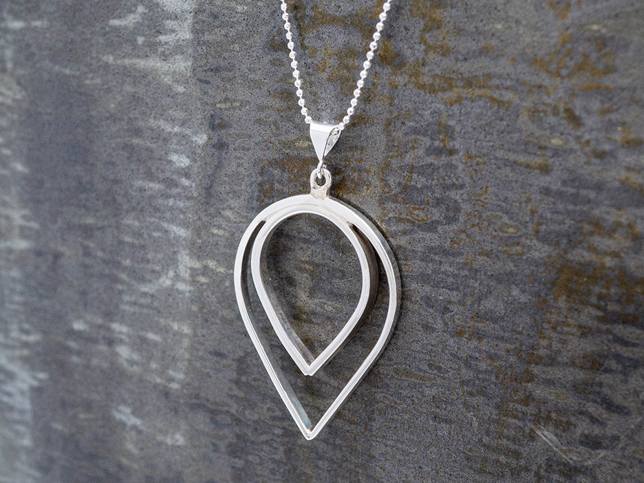 silver teardrop pendant on a dark gray surface