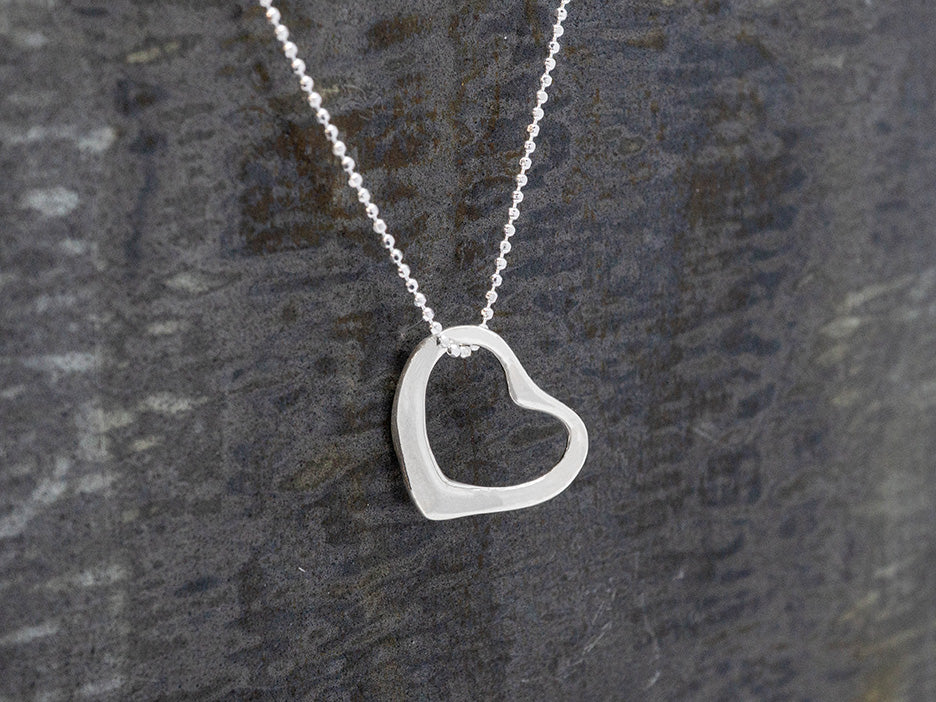 Silver heart-shaped pendant necklace on a gray background
