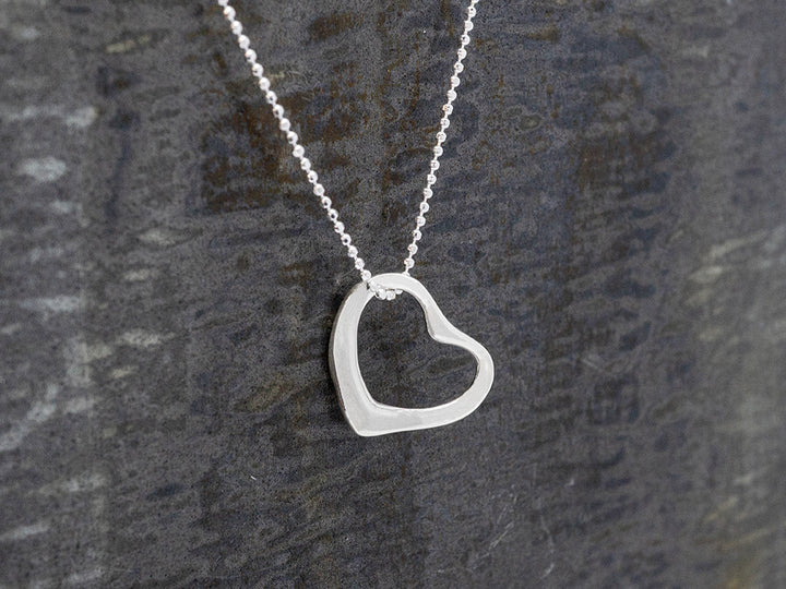 Silver heart-shaped pendant necklace on a gray background