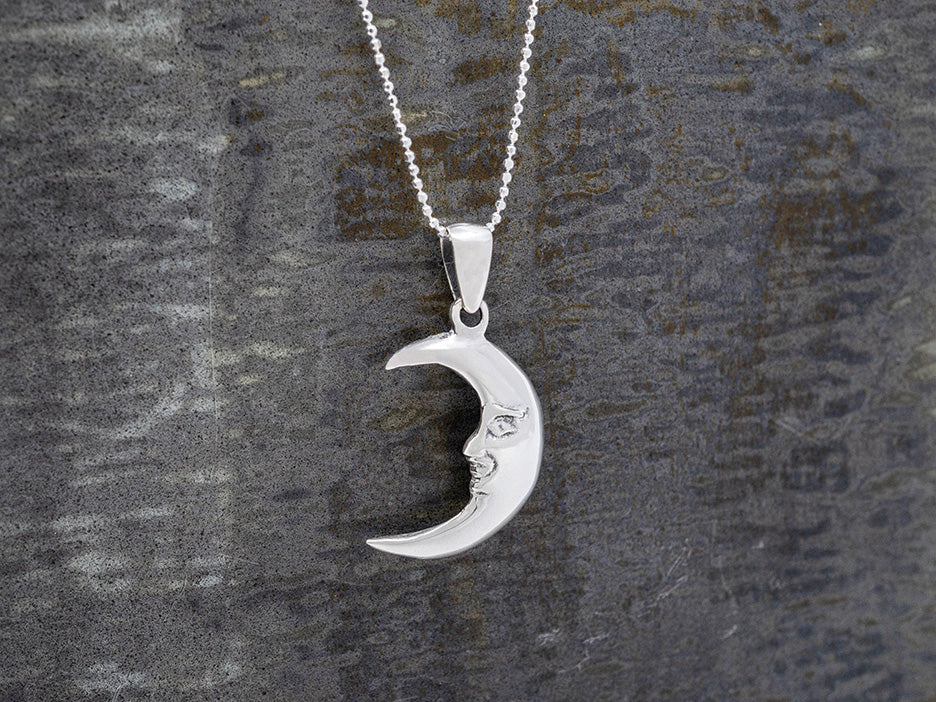 Silver crescent moon pendant necklace on dark background