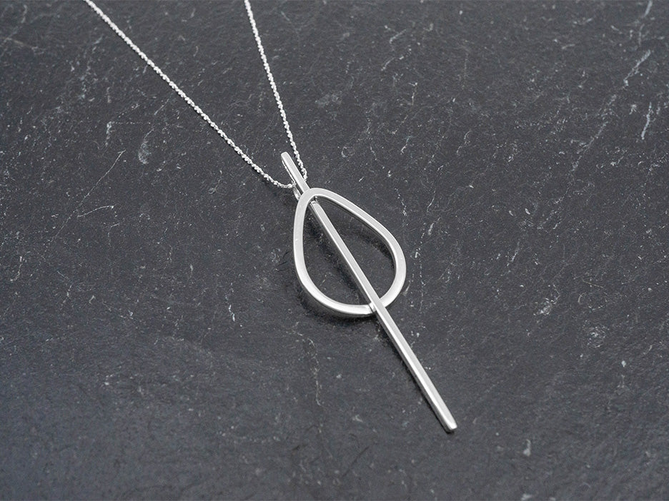 A bold geometric pendant hanging on a dainty sterling silver rope cut chain.
