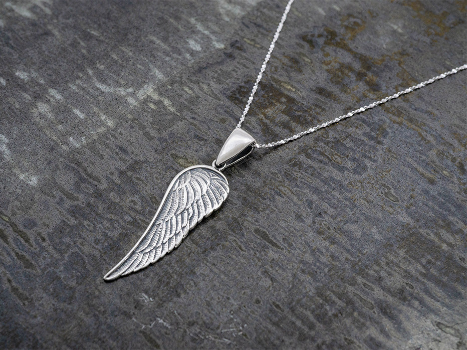 An angel wing pendant hanging on a dainty sterling silver rope cut chain.