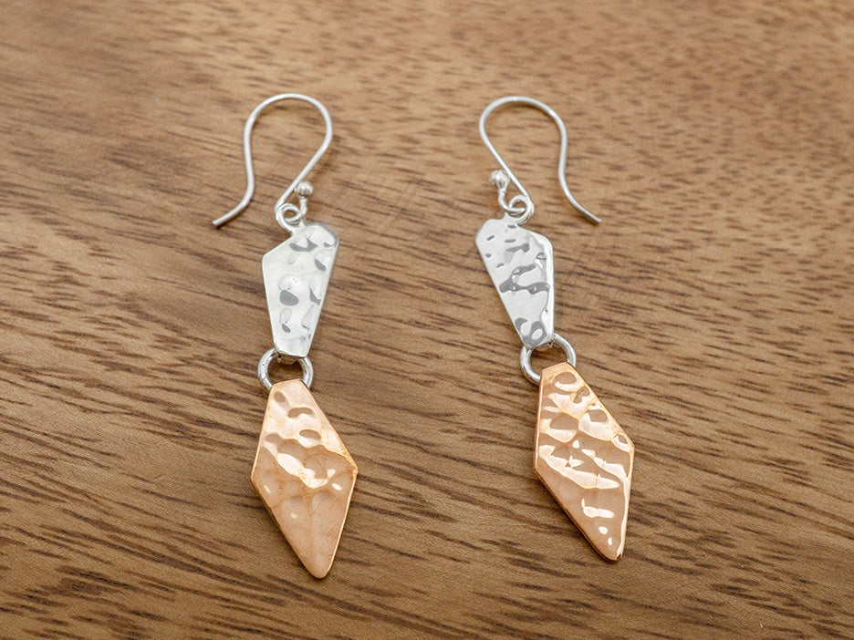 A two piece hammered earring with one silver piece and one copper piece.