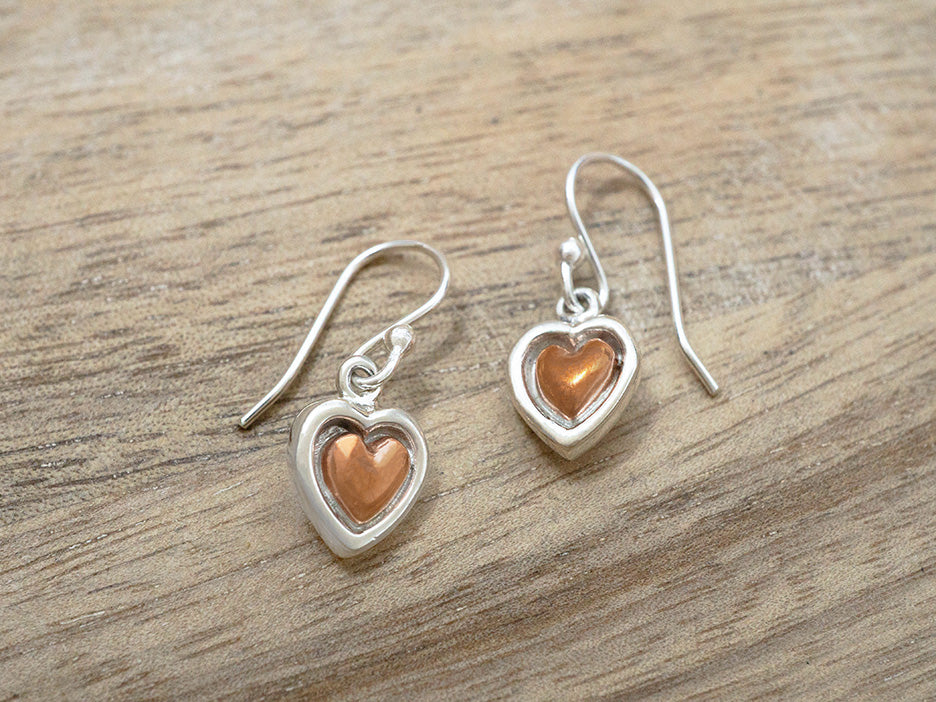 Petite sterling silver earrings featuring a copper heart in a silver frame on a hook.