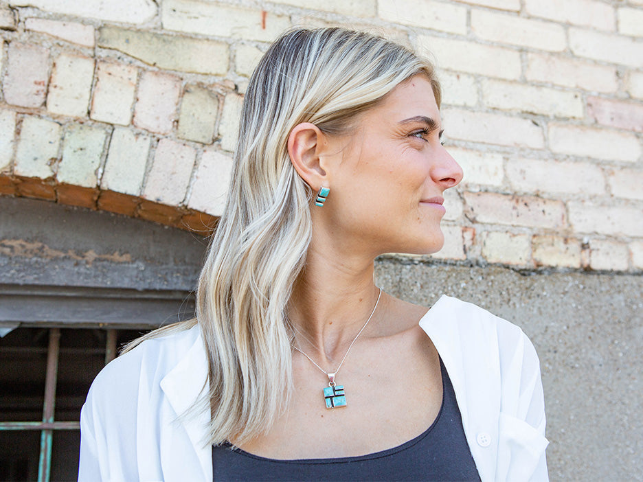 A model wearing a turquoise mosaic pendant and matching earrings.