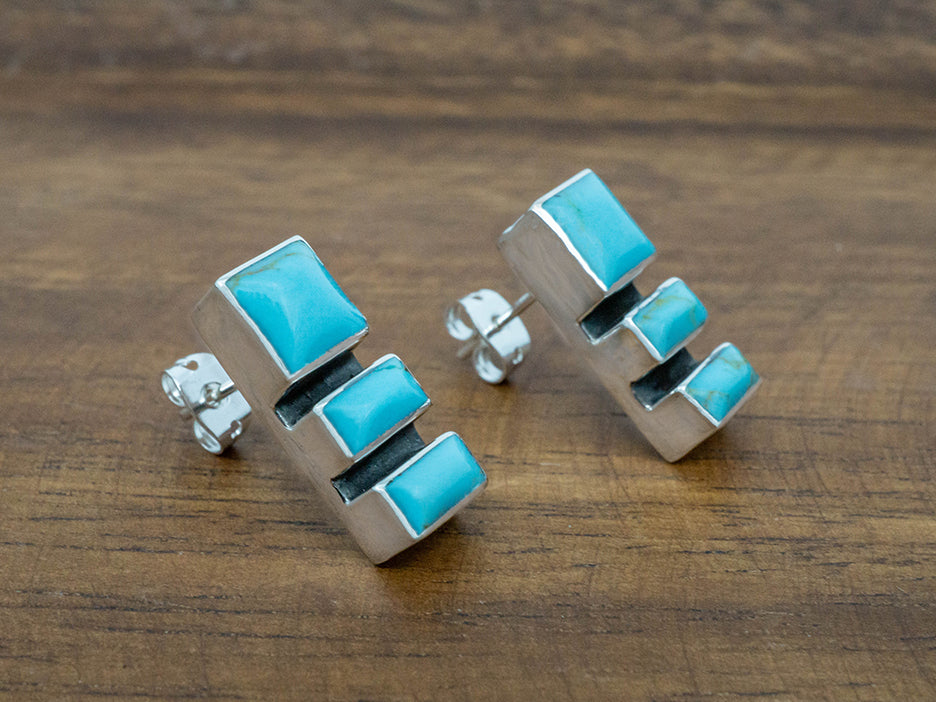 A sterling silver post earring featuring three turquoise stones.