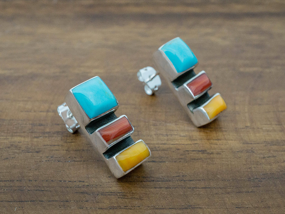 A pair of sterling silver earrings featuring three stones, one turquoise, one yellow and one coral.