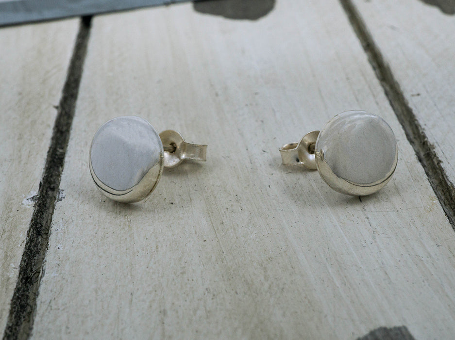 A pair of sterling silver earrings shaped like buttons.