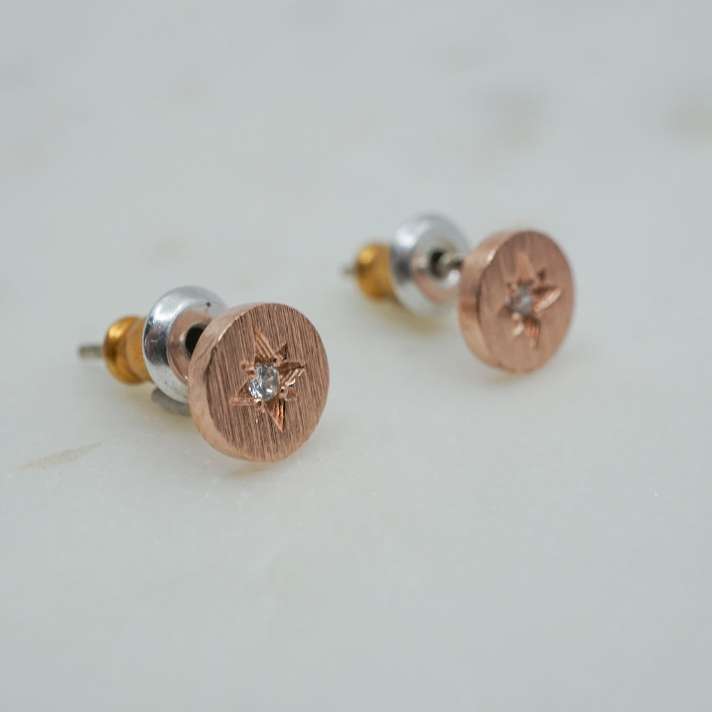 Tiny rose gold disc studs with a cubic zirconia star in the center.