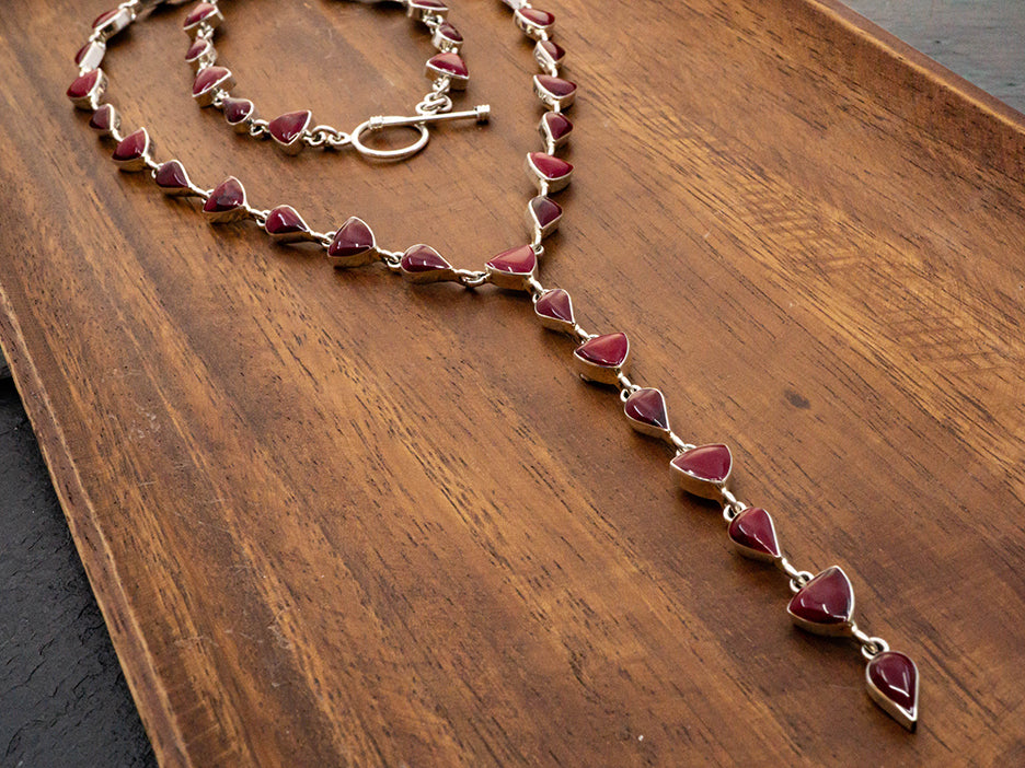 A sterling silver lariat necklace made with teardrop and trillion cut red jasper stones.