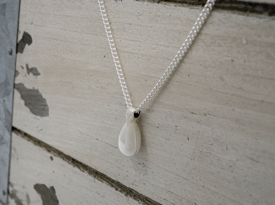 A dainty sterling silver necklace with a small teardrop in the center.