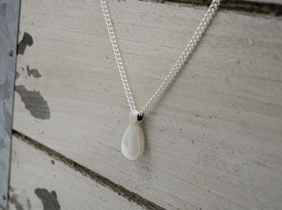 A close up photo of a dainty sterling silver necklace with a teardrop in the center.