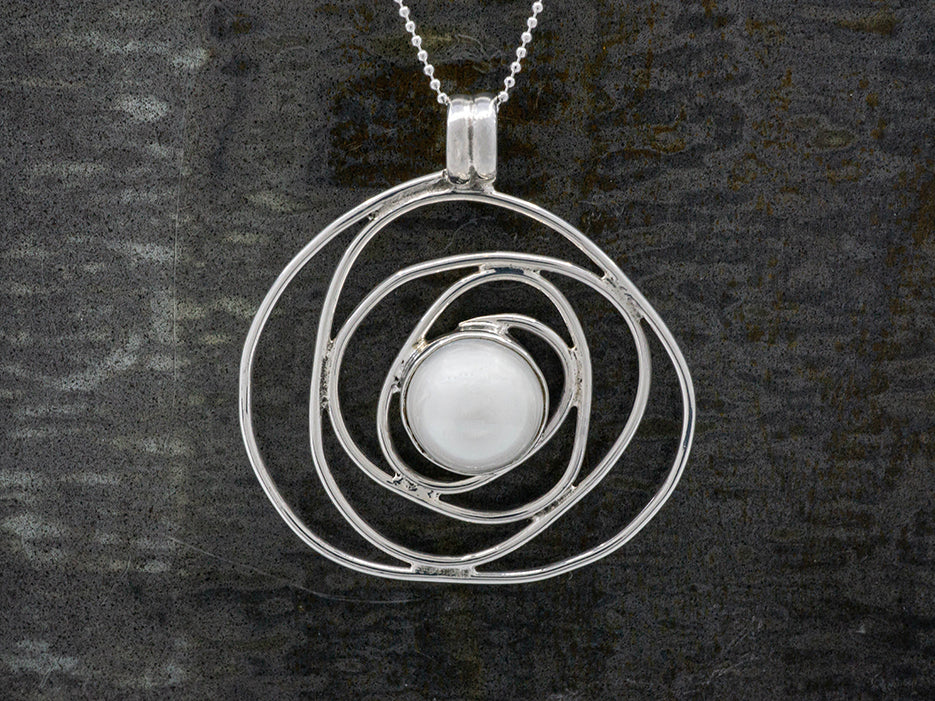 A swirling silver pendant with a pearl in the center