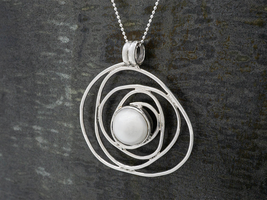 A swirling silver pendant with a pearl in the center